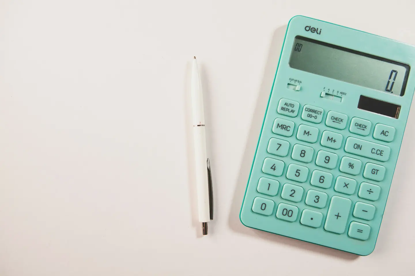 A calculator and a pen on a clean white desk