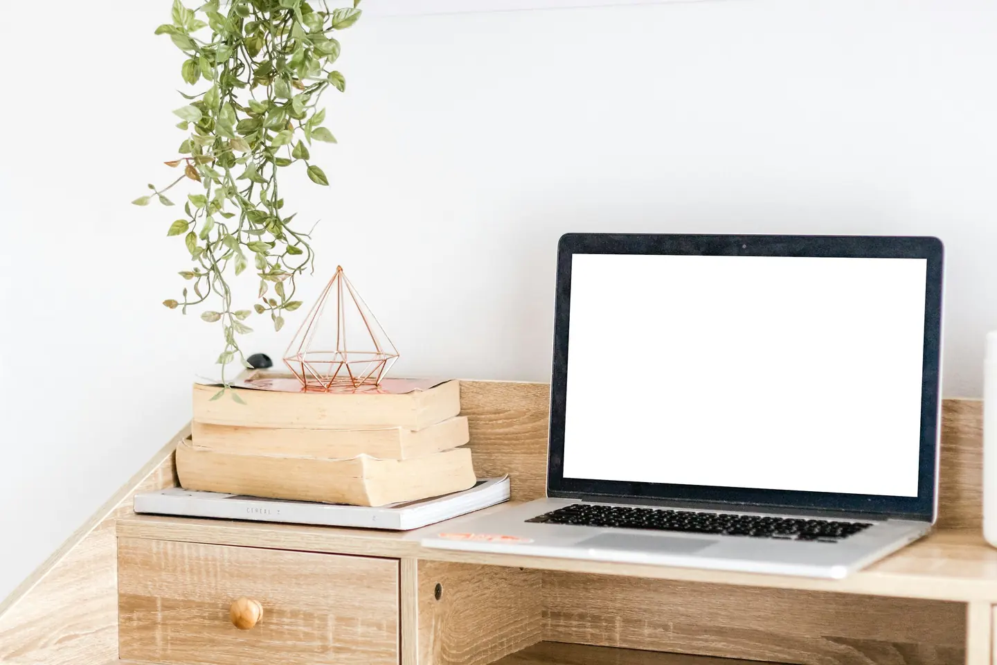 A laptop on a wooden desk in a bright, minimal workspace